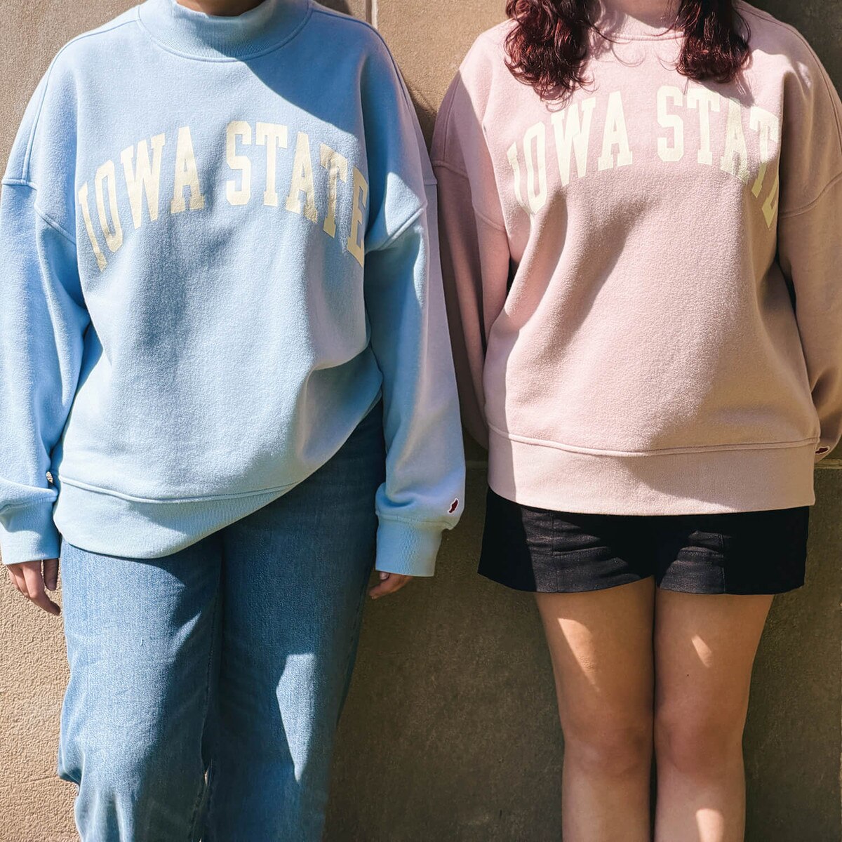 A student wearing League Women's Iowa State Dusty Pink Mock Neck Crew Sweatshirt with another student wearing the matching blue version